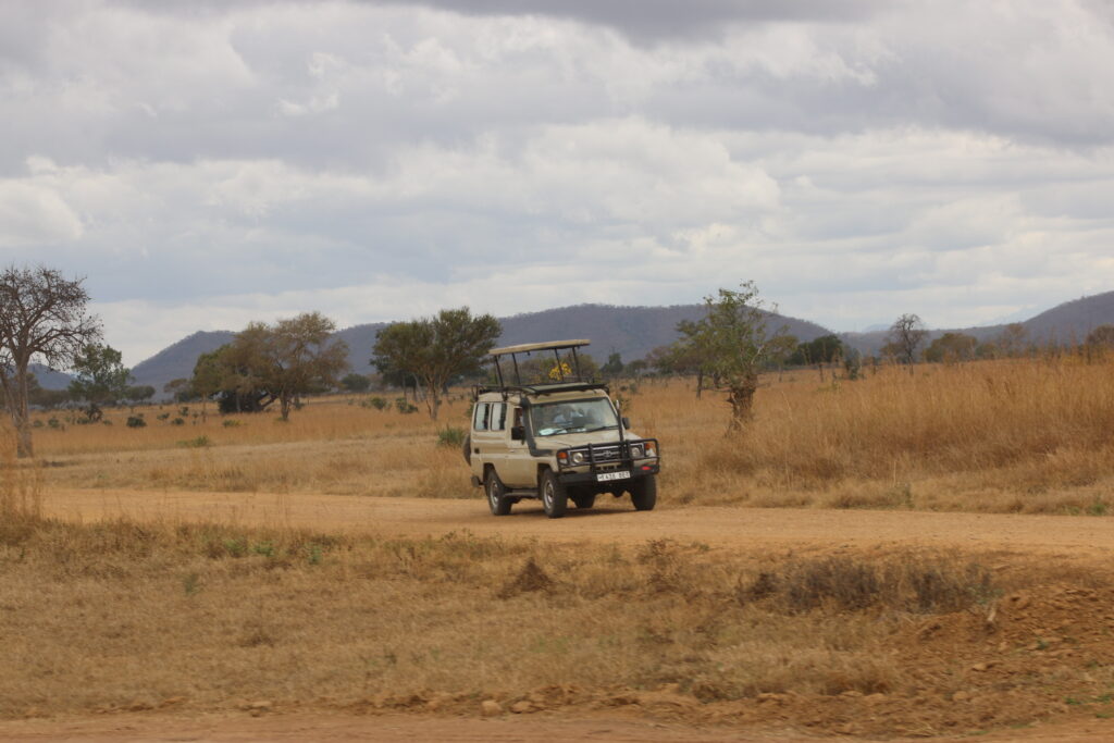 a professional safari jeep driving on a dirt road